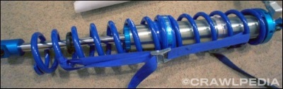 A photo of a dual rate King coilover with a tir down strap compressing both springs